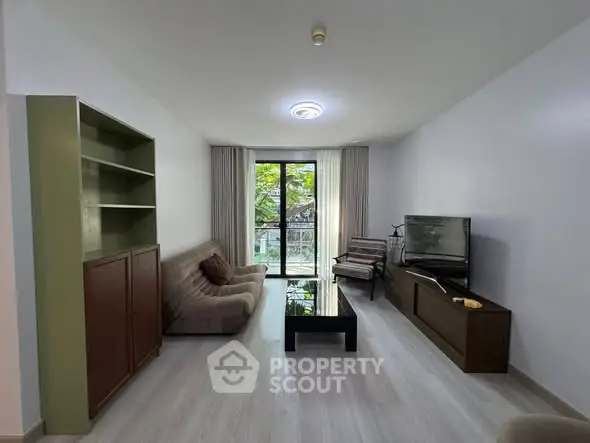 Spacious living room with modern furniture and large window offering natural light.