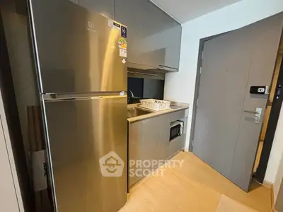 Modern compact kitchen with stainless steel appliances and sleek cabinetry in a stylish apartment.