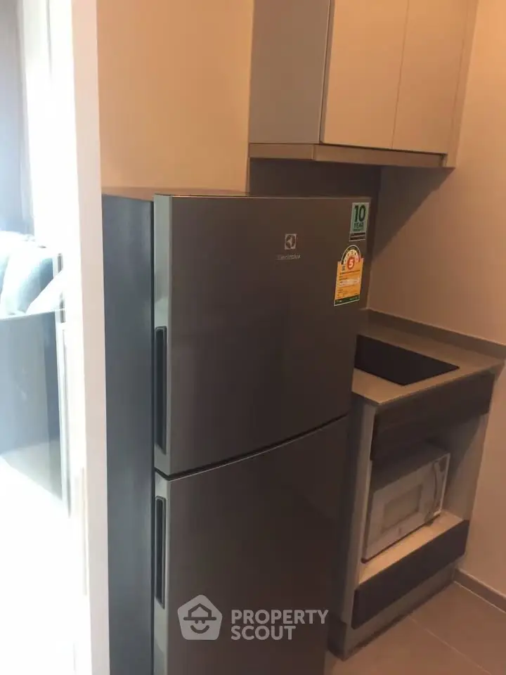 Modern kitchen with sleek fridge and built-in microwave in compact layout.