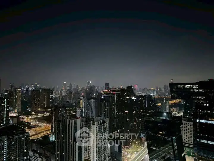 Stunning nighttime cityscape view from a high-rise building, showcasing vibrant urban lights and skyline.