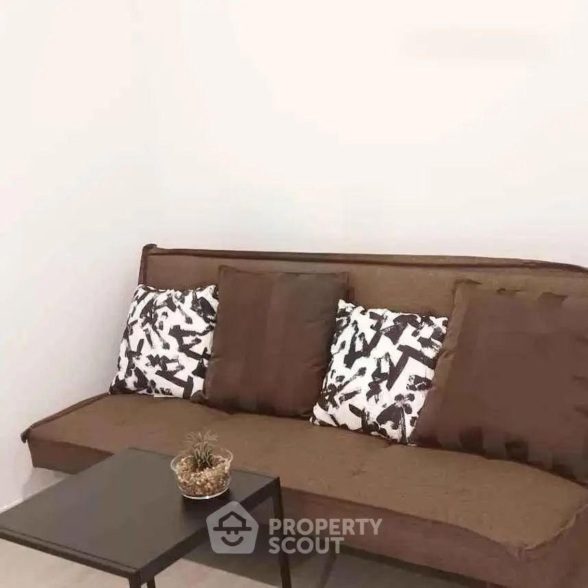 Modern living room with stylish brown sofa and decorative pillows, featuring a sleek coffee table and minimalist decor.