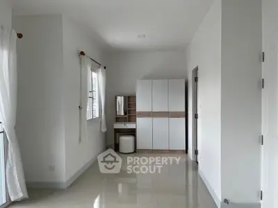 Spacious bedroom with modern wardrobe and vanity set, natural light through large windows.