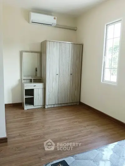 Spacious bedroom with wooden wardrobe and air conditioning unit.