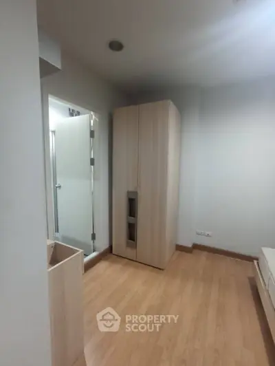 Modern minimalist bedroom with wooden flooring and sleek wardrobe