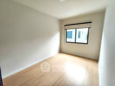 Spacious empty room with wooden flooring and large window, perfect for customization.