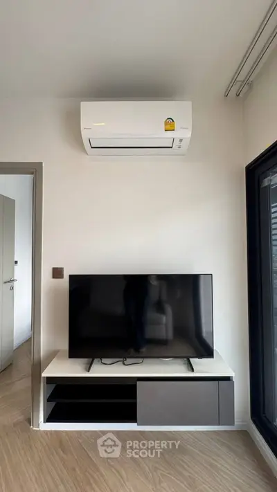 Modern living room with sleek TV setup and air conditioning unit, perfect for comfortable living.