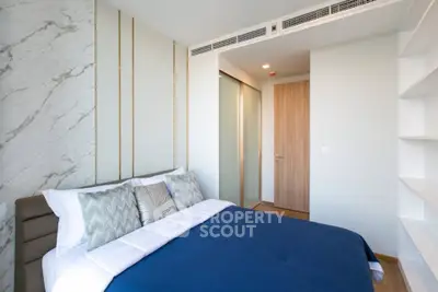 Modern bedroom with stylish decor and built-in shelving, featuring a cozy bed and elegant design.