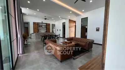 Spacious modern living room with elegant leather sofas and open kitchen layout, perfect for entertaining.