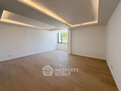 Spacious empty living room with modern ceiling lights and wooden flooring.