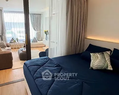 Modern bedroom with elegant decor and cozy living area, featuring floor-to-ceiling windows and stylish furnishings.