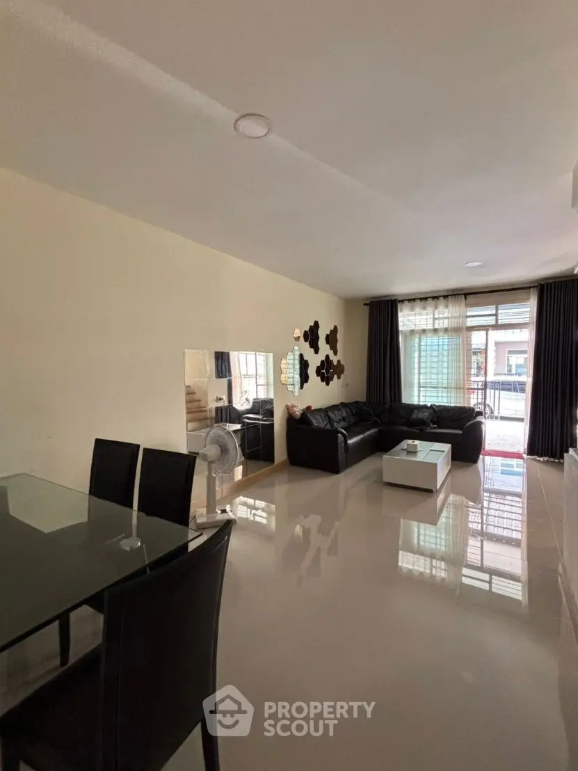 Spacious modern living room with sleek black furniture and large windows for natural light.