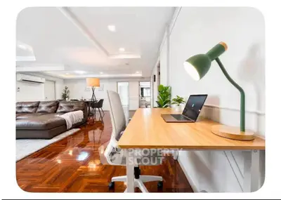 Spacious living room with modern furniture and a stylish home office setup, perfect for work and relaxation.