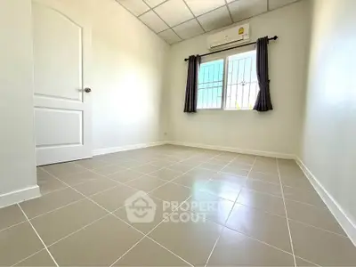 Spacious empty room with tiled floor and window, perfect for customization.