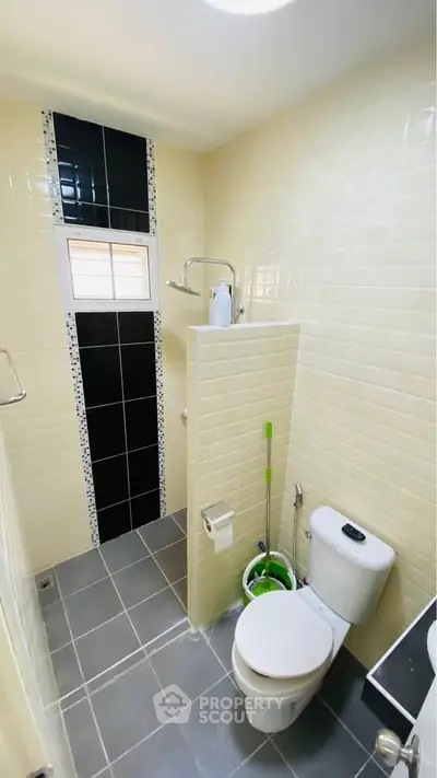 Modern bathroom with sleek black and white tiles, featuring a shower and toilet.