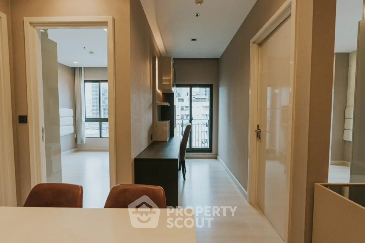 Modern apartment interior with study area and large windows offering city views.