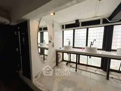 Spacious bathroom with dual sinks and large mirror, featuring modern fixtures and ample natural light.