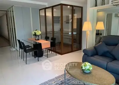 Modern living room with glass-enclosed kitchen and stylish decor