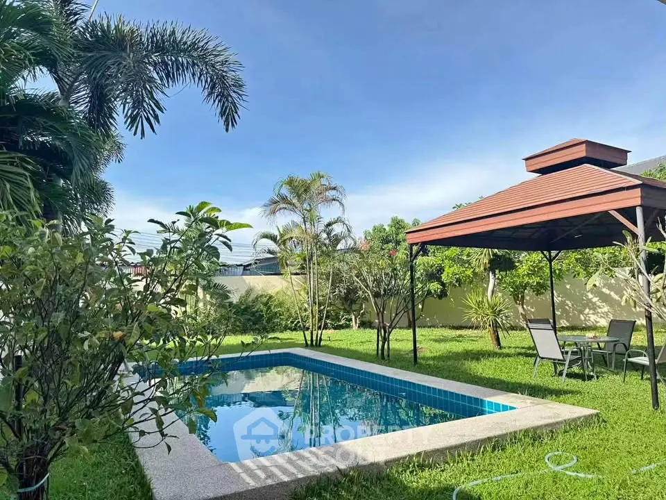 Charming backyard with a sparkling pool and gazebo, surrounded by lush greenery, perfect for relaxation and entertainment.