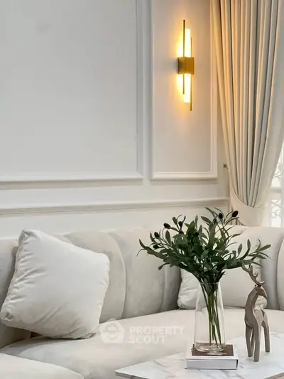 Elegant living room with plush sofa, wall sconce, and decorative accents