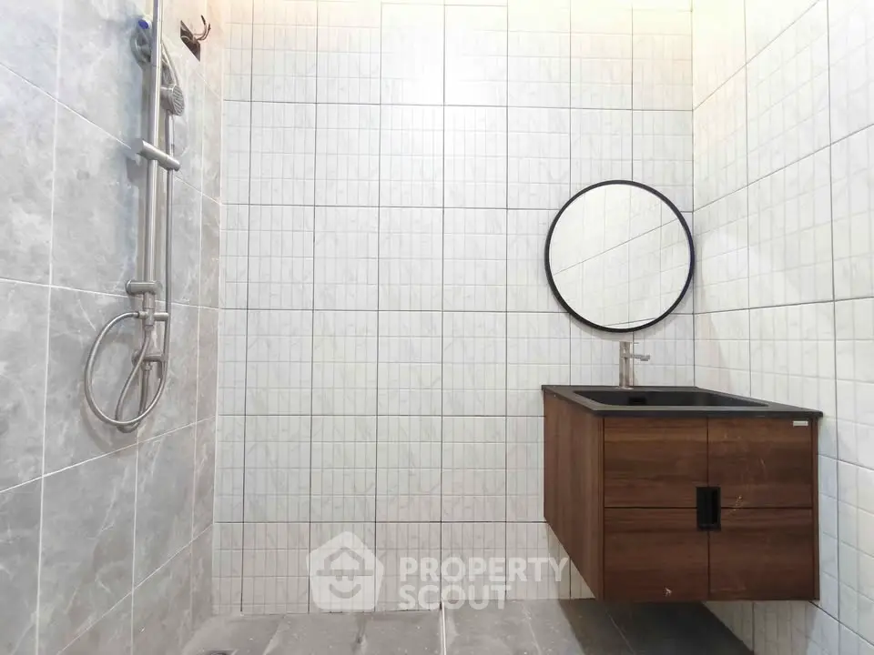 Modern bathroom with sleek vanity and round mirror, featuring elegant tile design.