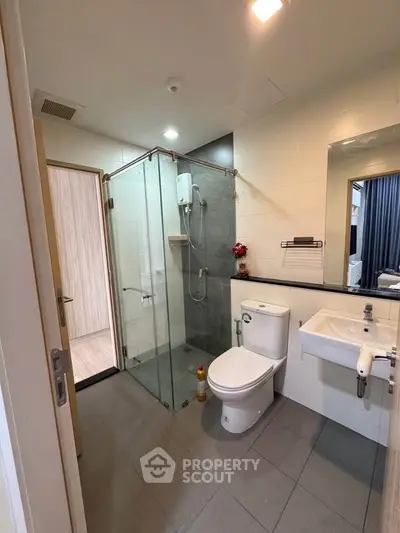 Modern bathroom with glass shower and sleek fixtures in contemporary apartment.