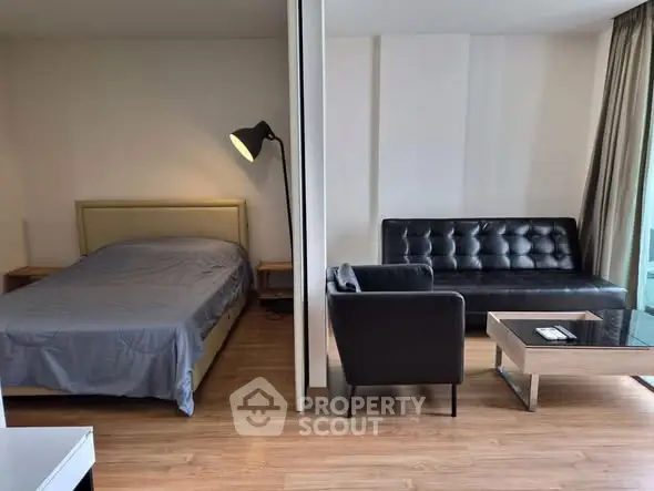 Modern studio apartment with cozy bedroom and stylish living area, featuring wooden flooring and contemporary furniture.