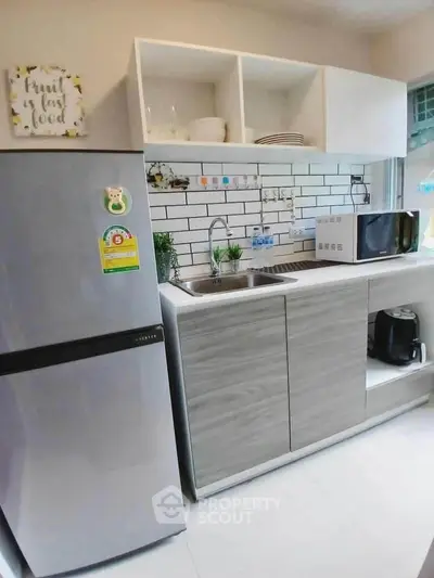 Modern kitchen with sleek cabinets, stainless steel fridge, and stylish backsplash.