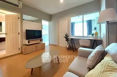 Modern living room with stylish decor and natural light, featuring a cozy sofa and sleek TV setup.