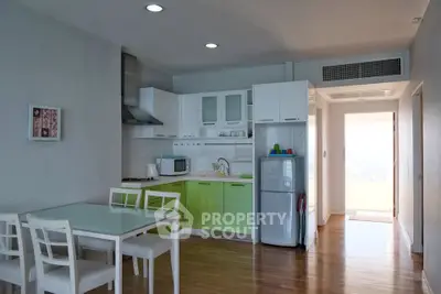 Modern kitchen with green cabinets, dining area, and natural light in a stylish apartment.