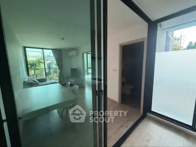 Modern living room with glass doors and natural light, featuring a cozy sofa and dining area.