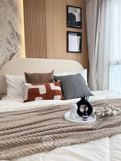 Luxurious bedroom with modern decor and cozy bedding, featuring stylish pillows and elegant wall art.