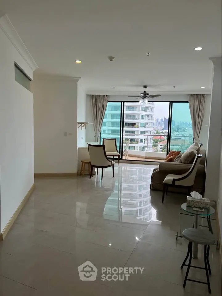 Spacious living room with large windows offering city views and elegant furnishings.