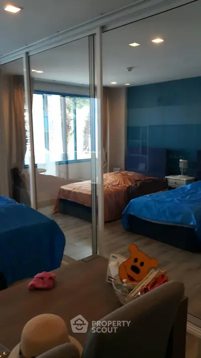 Spacious bedroom with twin beds and glass partition, modern decor and ample natural light.
