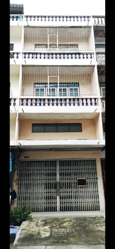 Charming multi-story building with gated entrance and balcony railings, ideal for urban living.
