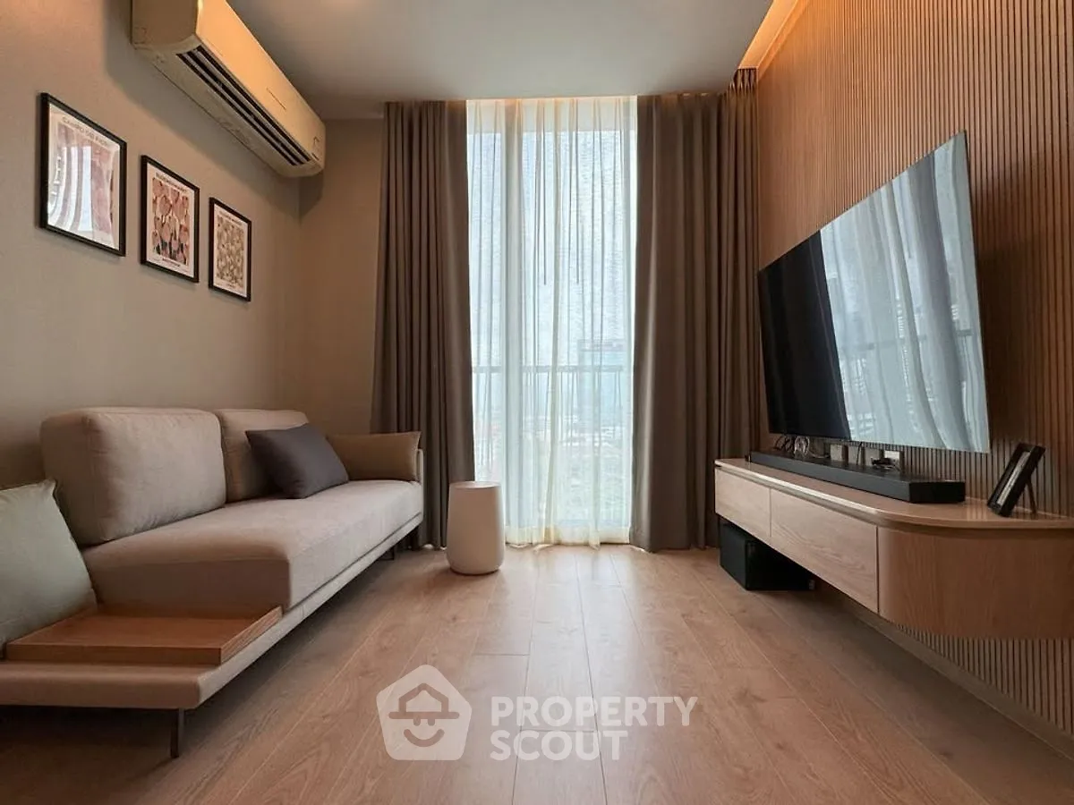 Modern living room with sleek design, featuring a large TV, stylish sofa, and floor-to-ceiling windows.