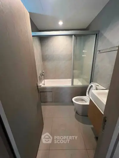 Modern bathroom with sleek design featuring a bathtub and glass shower enclosure.