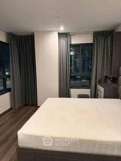 Modern bedroom with city view, featuring large windows and sleek furnishings.