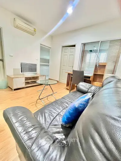 Modern living room with leather sofa and study area, ideal for urban living.