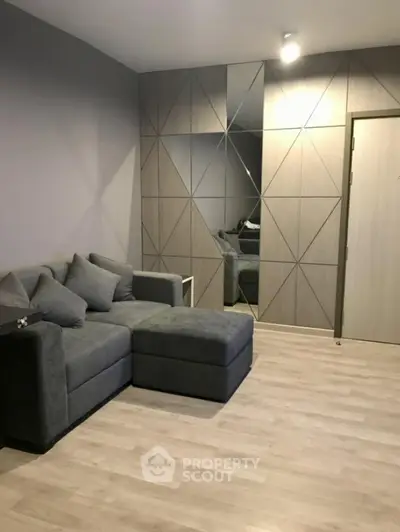 Modern living room with stylish geometric wall design and cozy grey sofa