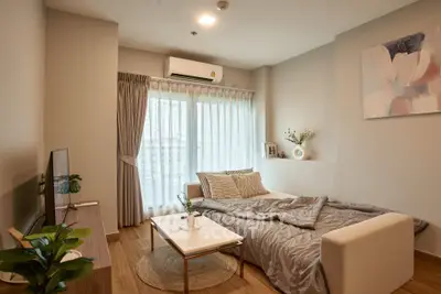 Cozy living room with sofa bed, modern decor, and natural light from large window.