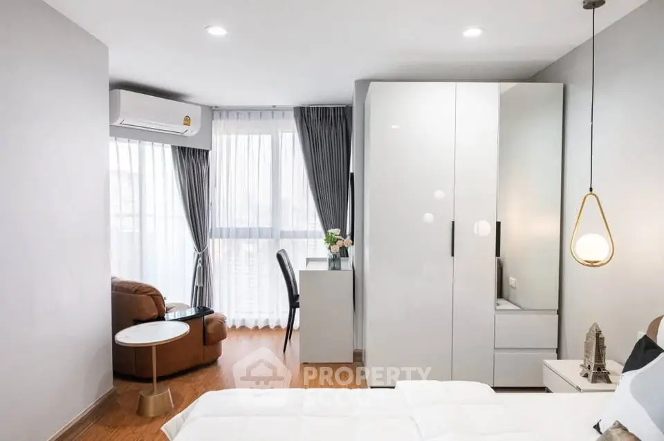Modern bedroom with large wardrobe, cozy seating area, and natural light from large windows.