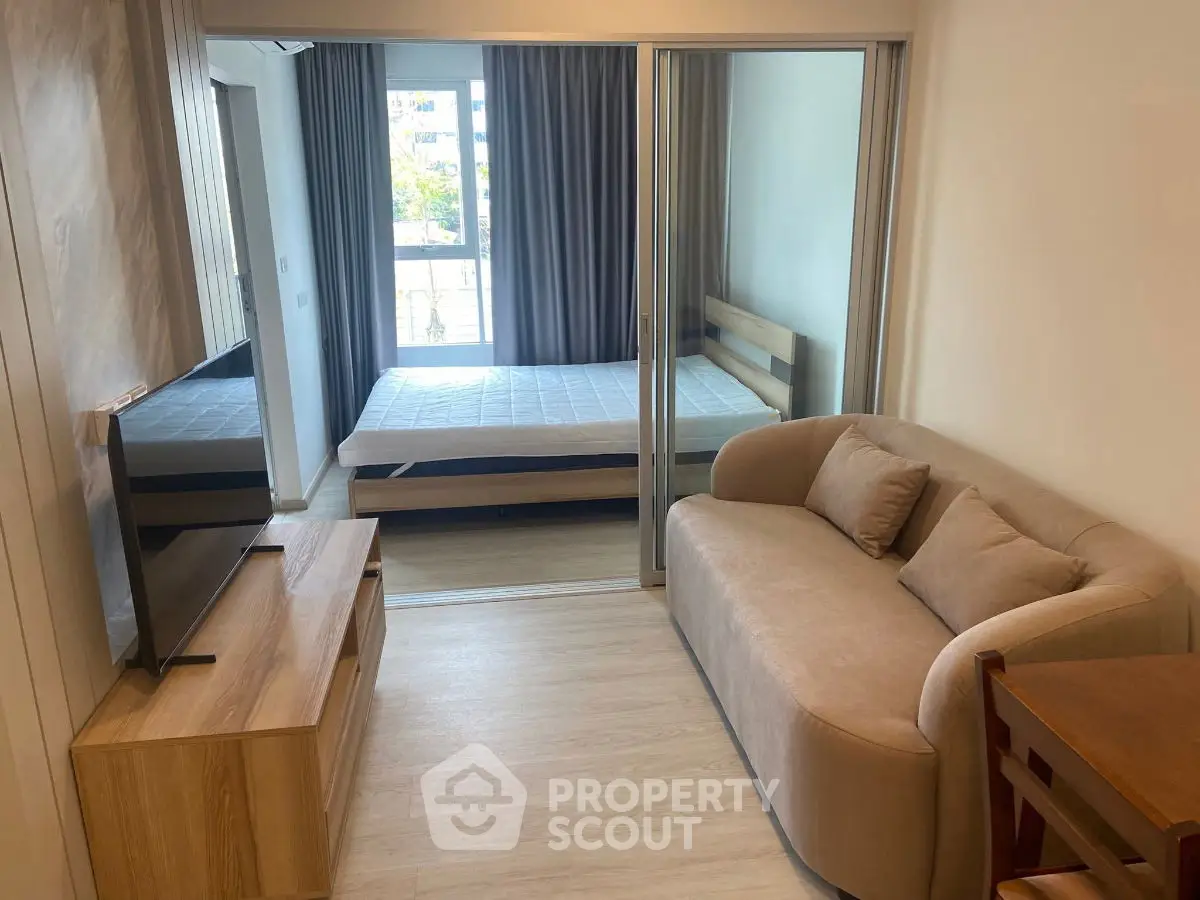 Modern studio apartment with cozy living area and bedroom separated by glass doors.