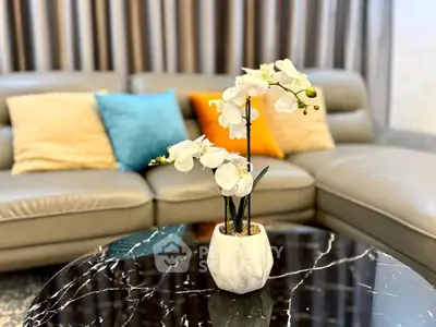 Stylish living room with elegant sofa and marble coffee table featuring a chic orchid centerpiece.