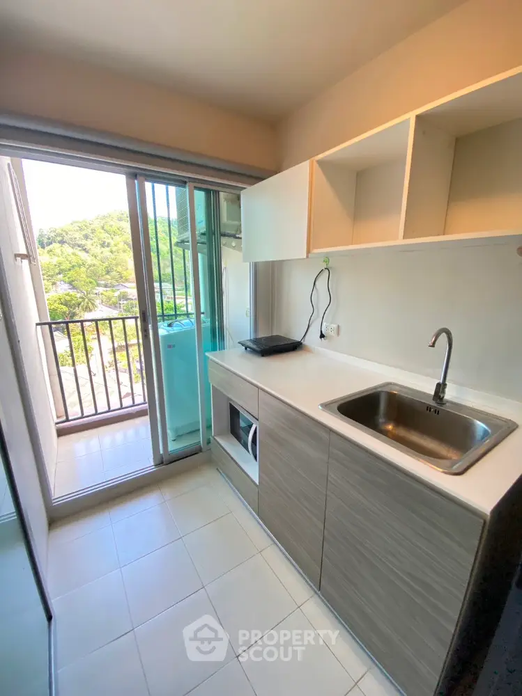 Modern kitchen with balcony view, featuring sleek cabinetry and built-in appliances.