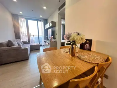 Modern living room with cozy sofa and dining area, featuring large windows and stylish decor.