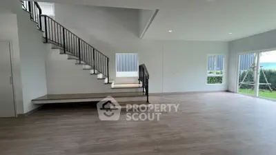 Spacious modern living room with elegant staircase and large windows overlooking garden.