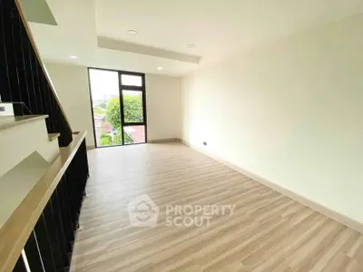 Spacious modern living room with large window and wooden flooring, perfect for natural light lovers.