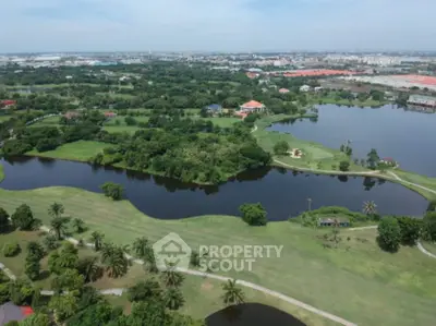 Stunning aerial view of lush green golf course with serene water features and expansive landscape.