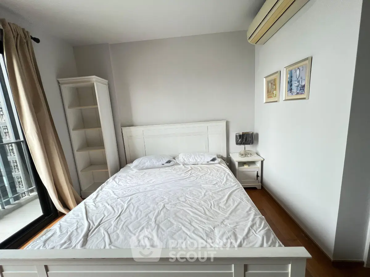 Cozy bedroom with white furniture and balcony access in modern apartment