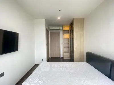 Modern bedroom with sleek design, featuring a wall-mounted TV and built-in wardrobe.